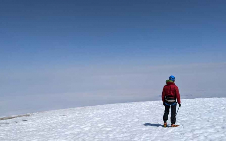 a person stands in a high, snowy field on a mountaineering course with outward bound